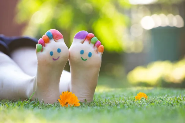 Barn Fötter Målade Med Färgglada Leende Ansikte Grönt Gräs — Stockfoto