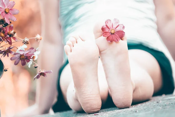 在花园的一个古老的浇灌罐旁边 一个脚趾头间挂着宇宙之花的孩子 — 图库照片