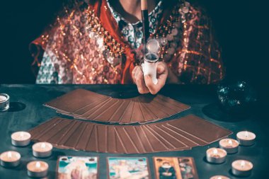 Falcı elinde mumların yanındaki masada tarot kartlarıyla. Tarot kartları kristal kürenin üzerine yayılmış. Tahmin konsepti..