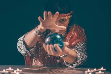 Falcı elinde mumların yanındaki masada tarot kartlarıyla. Tarot kartları kristal kürenin üzerine yayılmış. Tahmin konsepti..