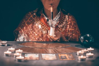 Falcı elinde mumların yanındaki masada tarot kartlarıyla. Tarot kartları kristal kürenin üzerine yayılmış. Tahmin konsepti..