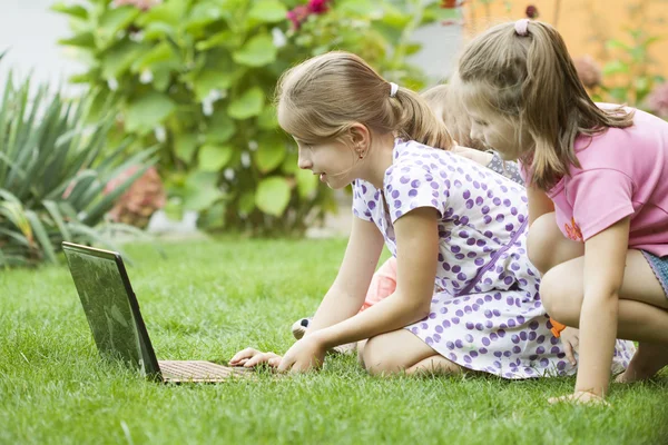 Дети, использующие ноутбук в саду — стоковое фото