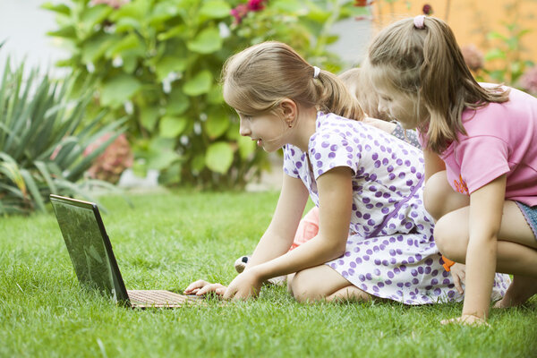 Children using laptop in garden