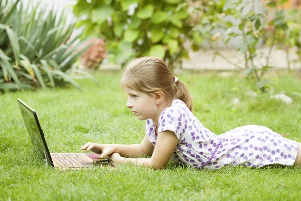 Meisje met laptop in tuin — Stockfoto