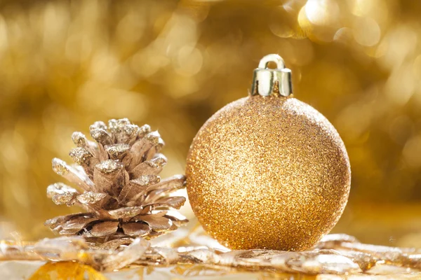 Christmas background with golden christmas ball and cone — Stock Photo, Image