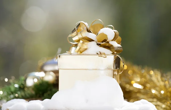 Goldene Weihnachtsgeschenkschachtel auf Schnee — Stockfoto