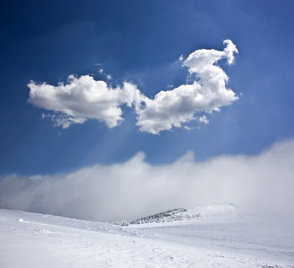 Vinterlandskap med snö täckte hill och blå himmel — Stockfoto