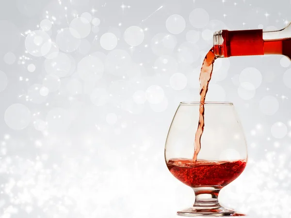 Pouring red wine and holiday lights — Stock Photo, Image