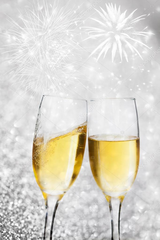 Champagne glasses against holiday lights and fireworks