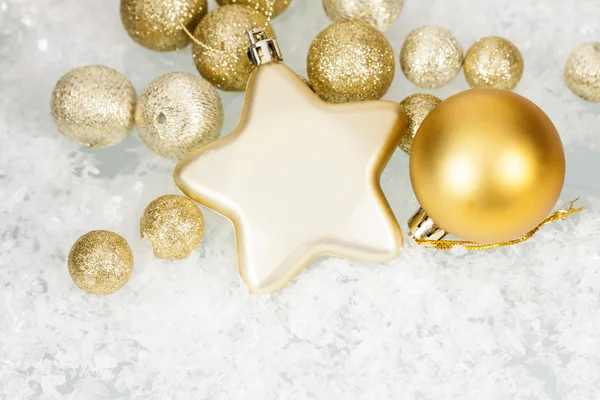 Gouden kerstballen en ster op ijzige achtergrond — Stockfoto