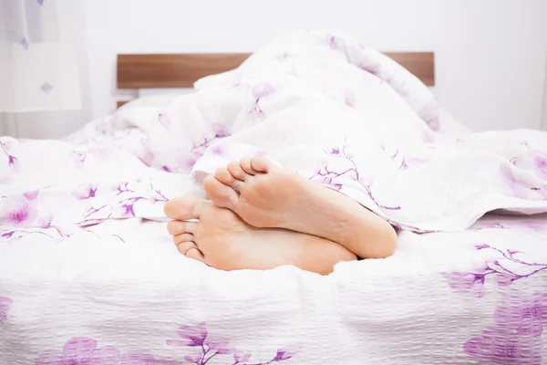 Woman feet under a white blanket — Stock Photo, Image