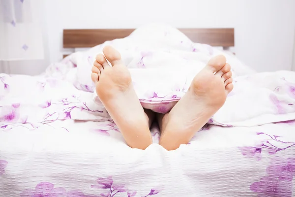 Woman feet under a white blanket — Stock Photo, Image
