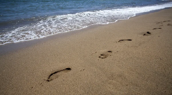 Voetstappen in het zand aan het strand — Stockfoto