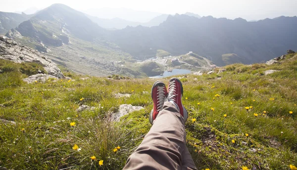 Jambes du voyageur assis sur le sommet de la montagne — Photo