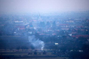 Picturesque village surrounded by autumn mist and smoke.