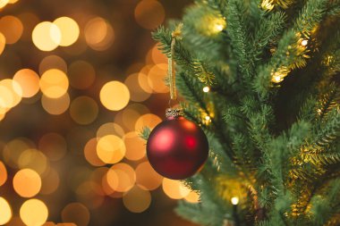 Christmas red ball on fir tree with bokeh holiday lights in the background with copy space