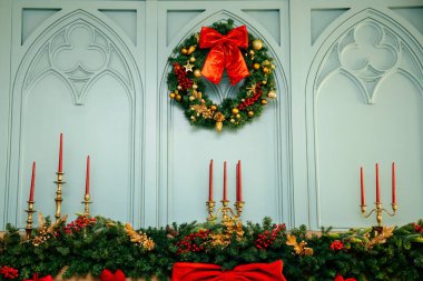 Evin arka planı Noel tatillerinde dekore edilmiş, şömineli oturma odası, Noel çelengi ve büyük kırmızı bir fiyonk..