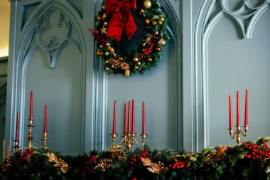 Evin arka planı Noel tatillerinde dekore edilmiş, şömineli oturma odası, Noel çelengi ve büyük kırmızı bir fiyonk..