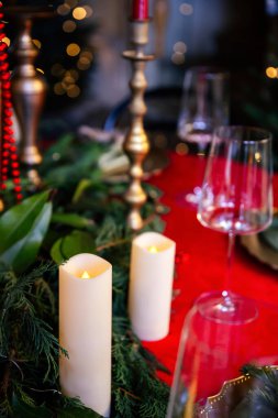 Şenlikli kırmızı ve Cooper aksanlı güzel düzenlenmiş Noel sofrasında mumların üzerine yakın plan..
