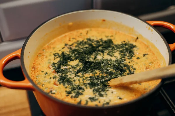 Mutfak ortamında bir tencere kremalı çorbaya doğranmış maydanoz ekliyorum..