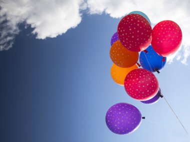 Mavi gökyüzüne uçan renkli balonlar