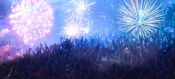 Nieuwjaarsconcept - juichende menigte en vuurwerk — Stockfoto