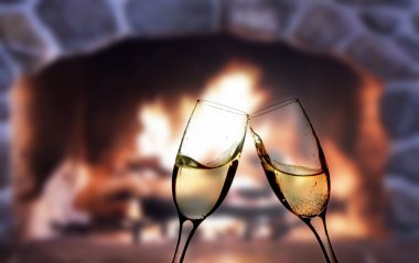 Glasses of champagne in front of warm fireplace