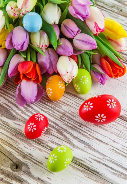 Tulipas coloridas com ovos de Páscoa na mesa de madeira . — Fotografia de Stock