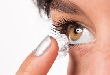 Genç bir kadın gözüne kontak lens takıyor..