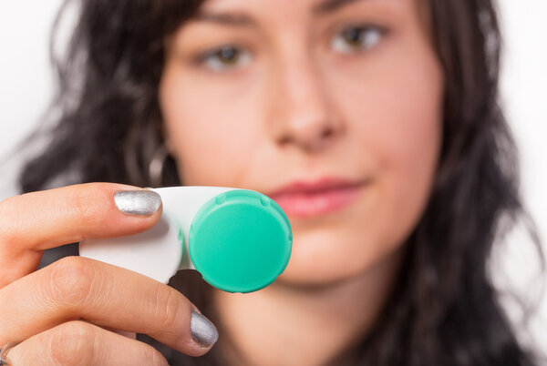 Young woman putting contact lens in her eye.