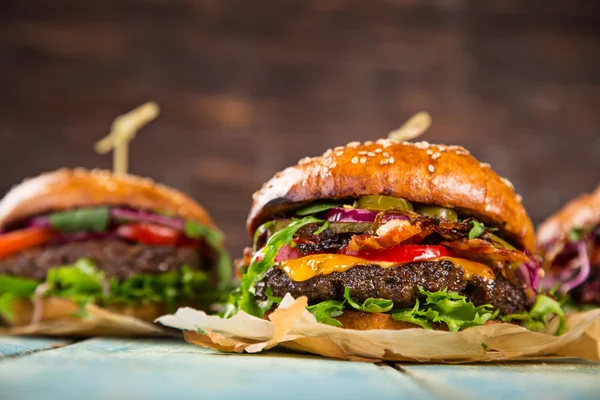 Smakliga hamburgare på träbord. — Stockfoto