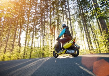 Adam sürme scooter orman yolu üzerinde.