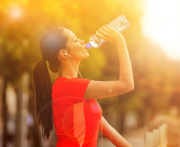 Молодая женщина пьет воду после пробежки по городу . — стоковое фото