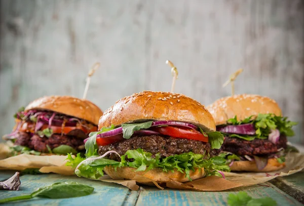 Sabrosas hamburguesas sobre mesa de madera. — Foto de Stock