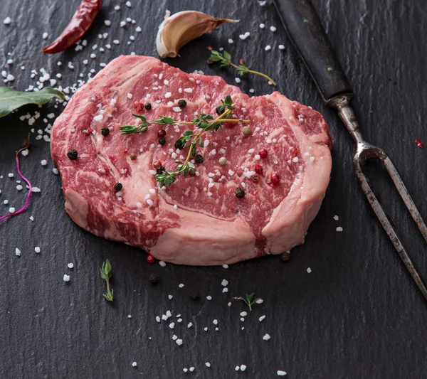 Delicious raw beef steak on black stone table. — Stock Photo, Image