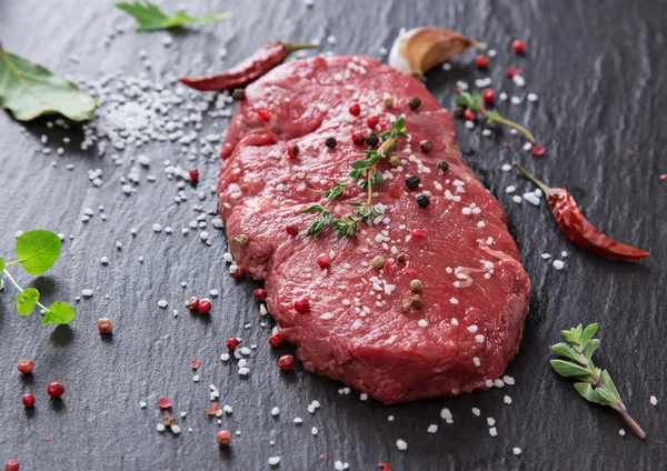 Delicioso bife cru na mesa de pedra preta . — Fotografia de Stock