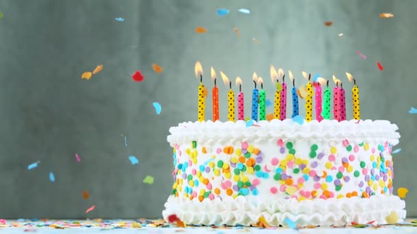 Gâteau d'anniversaire avec des bougies colorées brûlantes sur fond gris. Super ralenti. — Video