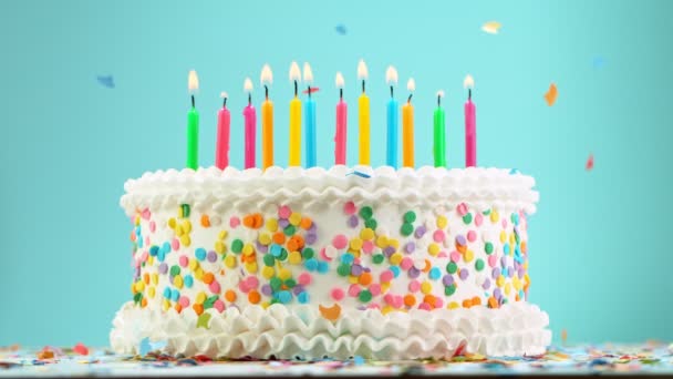 Födelsedag tårta med brännande färgglada ljus på pastell blå bakgrund. Superlångsamma rörelser. — Stockvideo