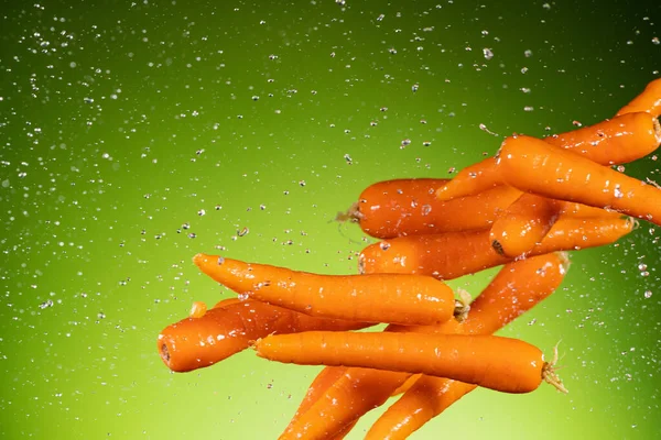 Zanahorias frescas volando, aisladas sobre fondo verde. — Foto de Stock