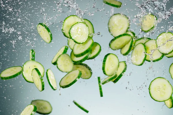 Congelar el movimiento del pepino volador en el aire con salpicaduras de agua — Foto de Stock