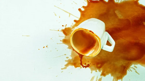 Café derramado con una taza pequeña sobre una mesa blanca - paño —  Fotos de Stock