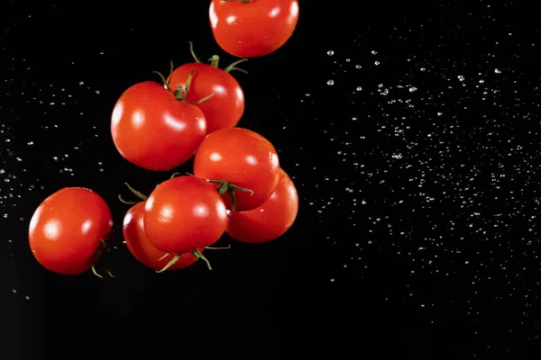 Uçan kiraz domatesleri, siyah arka planda izole edilmiş.. — Stok fotoğraf