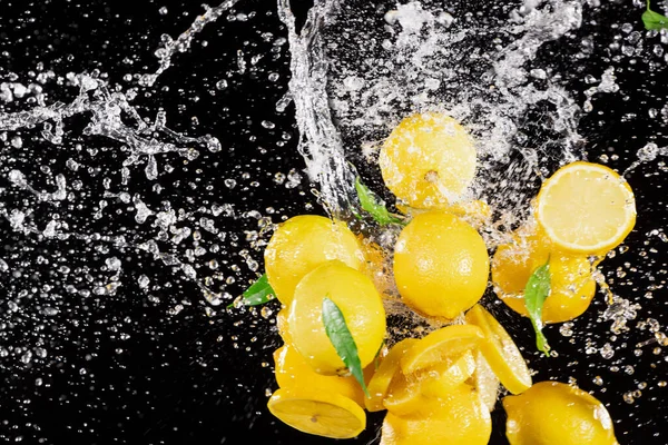Замораживание движения свежих лимонов с брызгами воды — стоковое фото