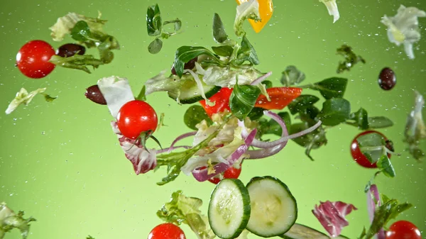 Flying vegetable salad isolated on green background. — Stock Photo, Image
