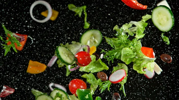 Salade de légumes volants isolée sur fond noir. — Photo