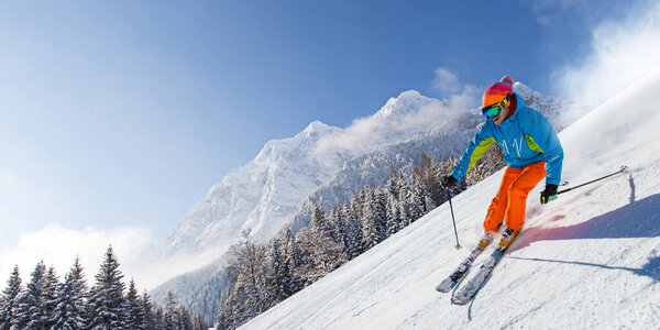 Skier skiing downhill in high mountains