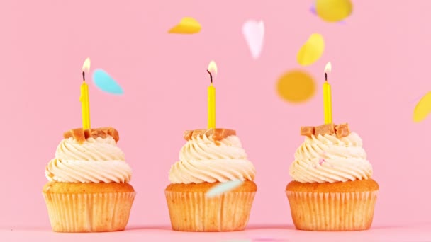 Cupcake con candele colorate brucianti su sfondo rosa pastello. Super rallentatore. — Video Stock