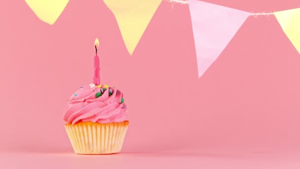 Cupcake con bruciante candela colorata su sfondo rosa pastello. Super rallentatore. — Video Stock