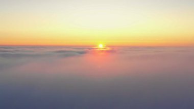 Gün doğumunda ilk güneş ışınlarıyla güzel beyaz bulutların üzerinden uç..