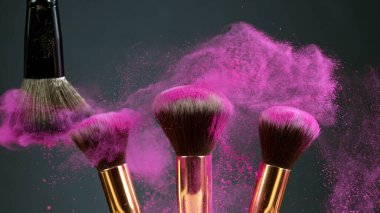 Makyaj fırçaları koyu arkaplanda birbirine dokunur